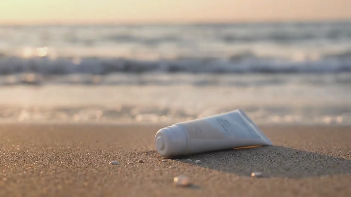 Load video: Dead Sea mud mask for acne-prone skin, shown on sand with ocean waves in the background